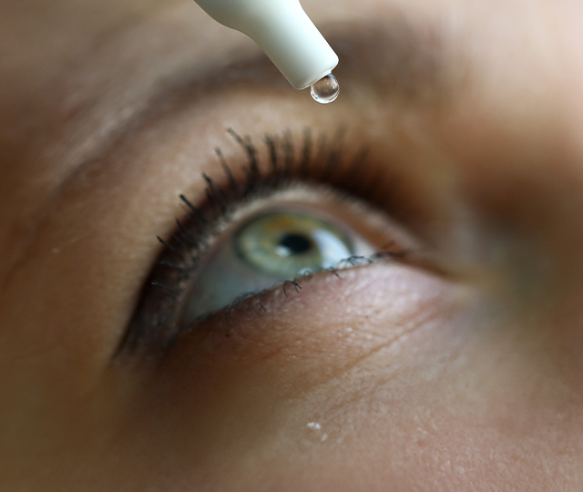  A woman placing a contact lens into her left eye.